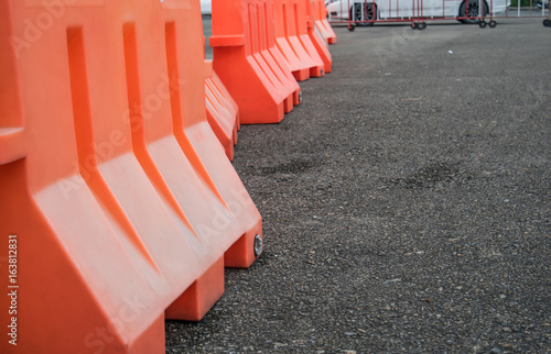 Orange plastic barrier lined up on the road - selective focus