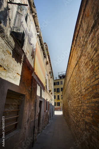 Laundry hanging in an alleyway in downtown Venice, Italy. Orange brick in daylight captured with a Canon 5D on a 17-40mm wide angle lens. photo