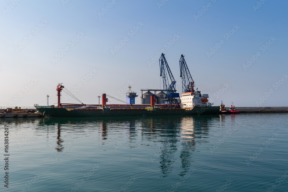 Big cargo ship in sea port terminal with cranes in Balchik, Bulgaria