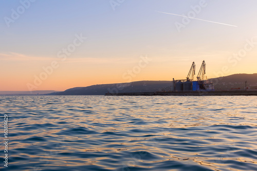 View of the sea port terminal with cranes at sunset time in Balchik, Bulgaria