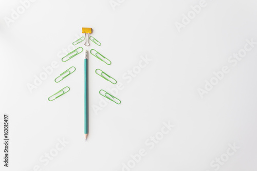 pencil and paper clip lay like a Christmas tree on white background