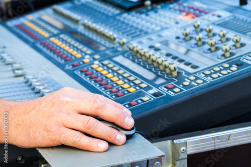 Close view of man using mixing console and computer mouse