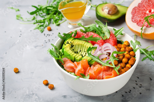 Healthy salad bowl with salmon, grapefruit, spicy chickpeas, avocado, red onion and arugula