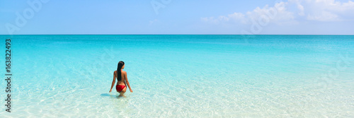 Beach luxury travel getaway resort vacation banner. Bikini woman relaxing enjoying tropical holidays swimming in turquoise ocean water in paradise destination.