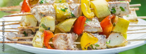 Tasty skewers of fresh fish with vegetables and apples on a wooden shish kebab