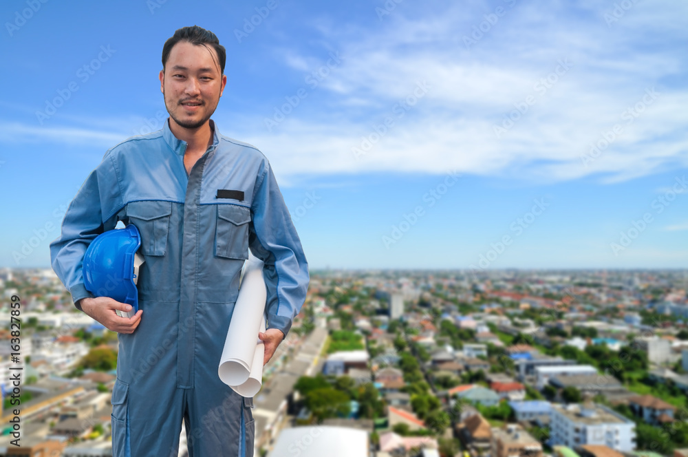 Young engineer standing holding city plan in front of Cityscape view with blue sky, Bangkok Thailand. Young engineer standing holding city plan in front of Cityscape view with blue sky, Bangkok Thailand.