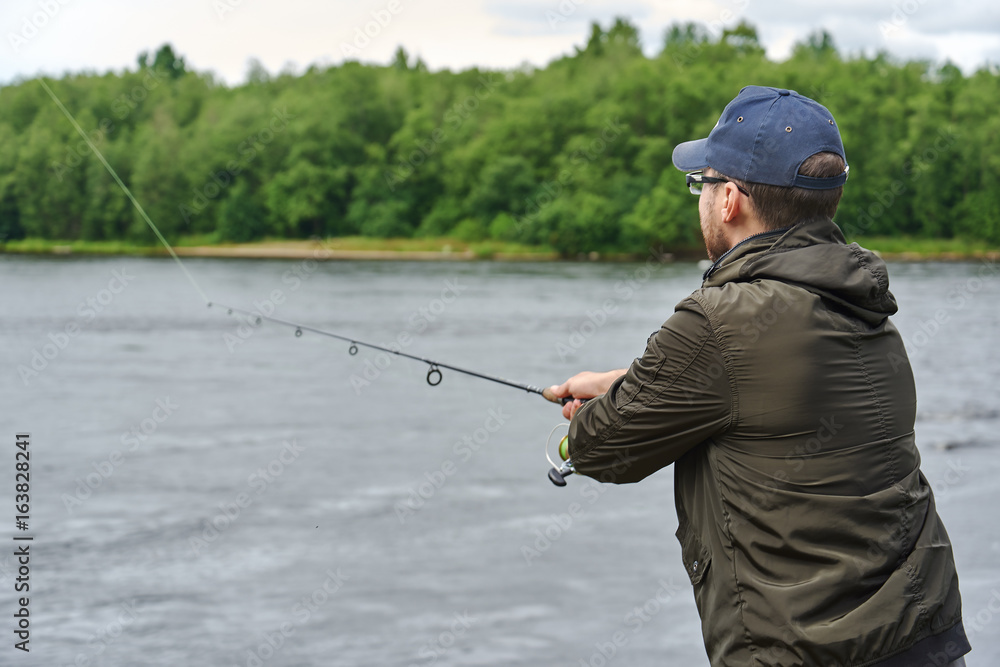 Man fishing with spinning rod in a rapid river. Man fishing with spinning rod in a rapid river.