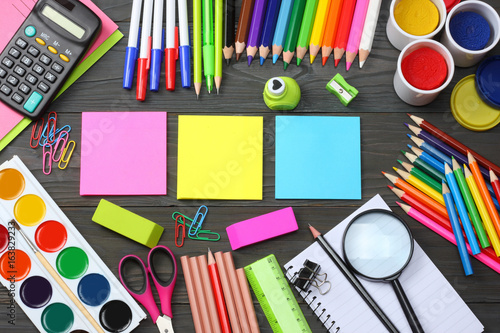 school and office supplies. school background. colored pencils, pen, pains, paper for school and student education on dark wooden background. top view with copy space
