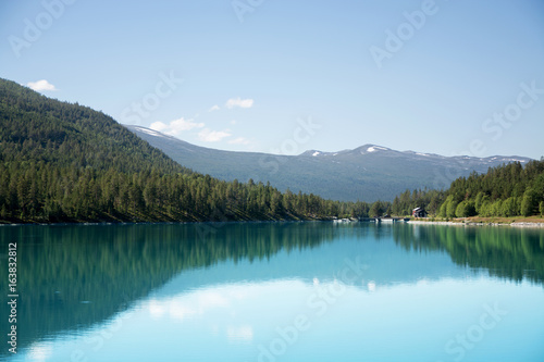 Reflections on Norwegian lake with forest and moutains