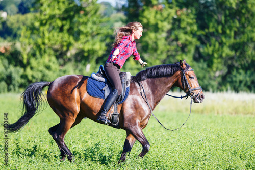 Young rider woman on galloping horse without holding bridle. Free riding equestrian background