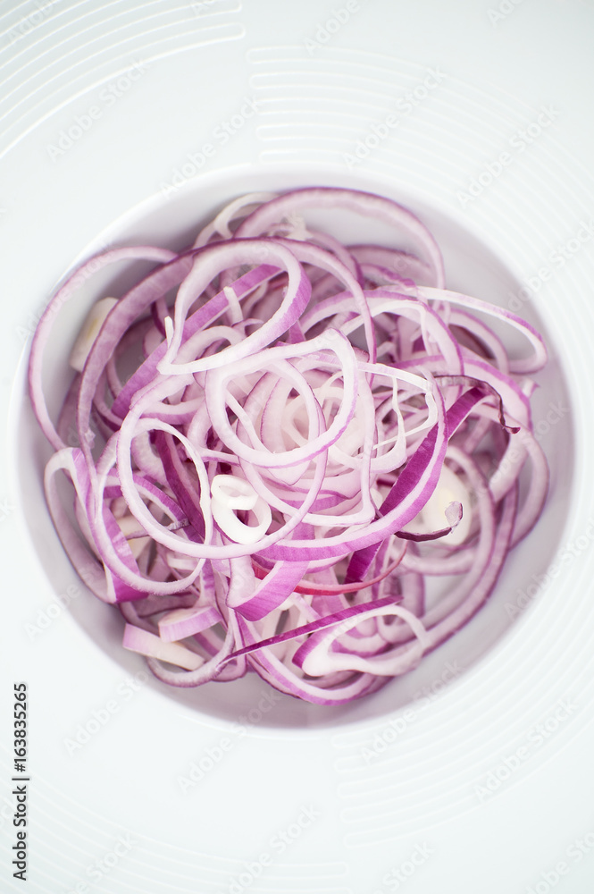 Sliced ​​red onion in a white plate close-up..