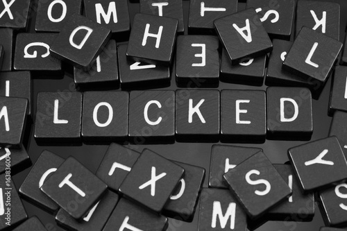 Black letter tiles spelling the word "locked" on a reflective background