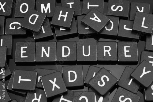 Black letter tiles spelling the word "endure" on a reflective background