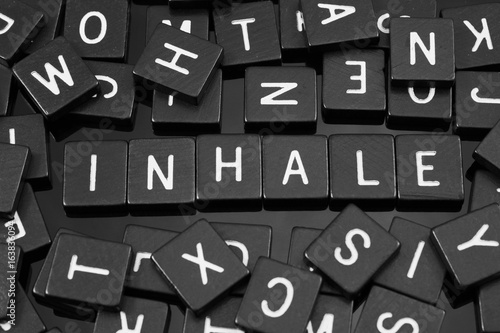 Black letter tiles spelling the word "inhale" on a reflective background