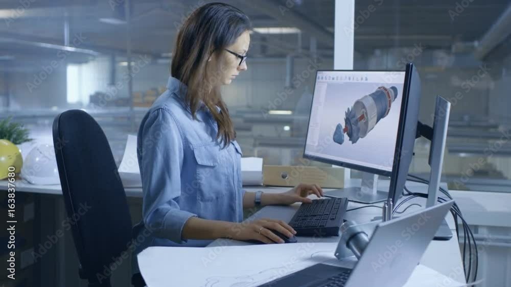 Female Industrial Engineer Designs 3D Turbine/ Engine with Computer Software. Inside of the Factory is Seen From Her Office Window. Shot on RED EPIC-W 8K Helium Cinema Camera. Female Industrial Engineer Designs 3D Turbine/ Engine with Computer Software. Inside of the Factory is Seen From Her Office Window. Shot on RED EPIC-W 8K Helium Cinema Camera.