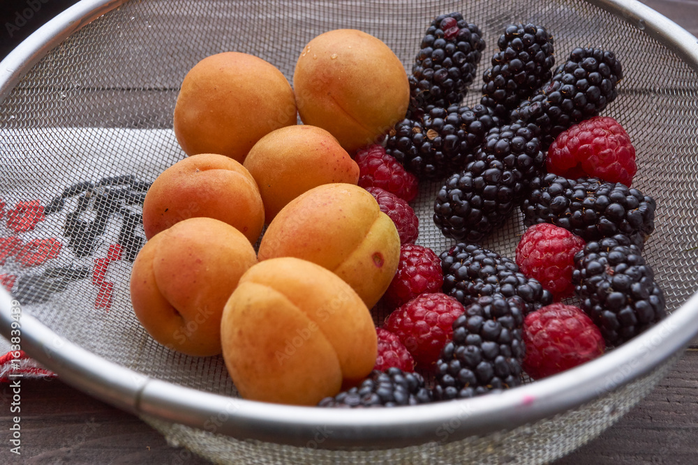 colander with the washed-up berries raspberry and blackberry and apricots colander with the washed-up berries raspberry and blackberry and apricots