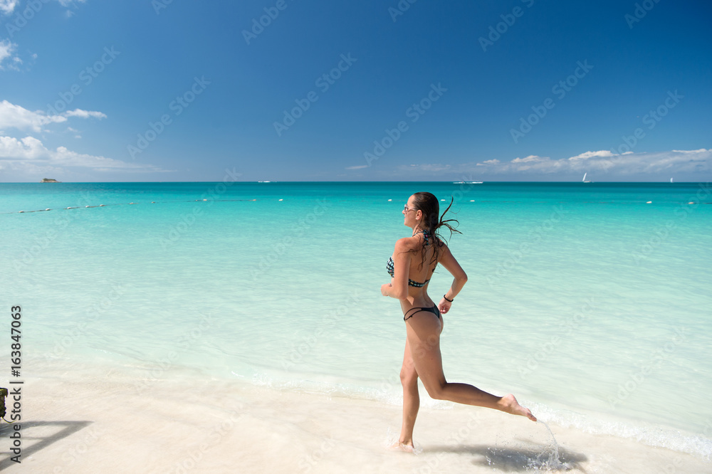 Girl in bikini running on beach