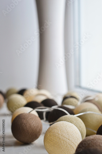 Cotton light balls decoration with brown, beige and white balls in the home interior. Natural light from window.