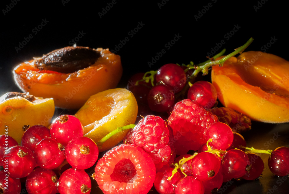 Fresh fruits and berries such as apricot, raspberry red currant on a black background Fresh fruits and berries such as apricot, raspberry red currant on a black background