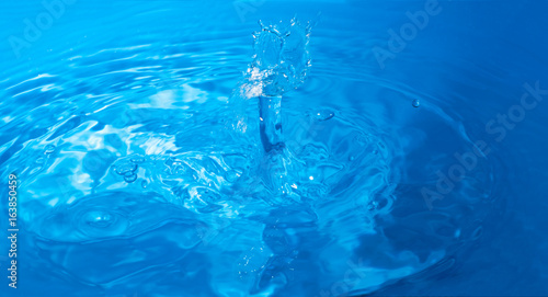 Texture of a drop falling into the blue water, close-up