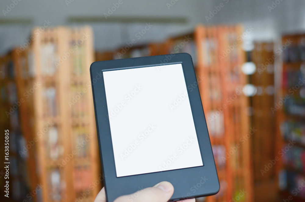 Hand holding ebook reader with white screen in classic library with traditional books. Place for text