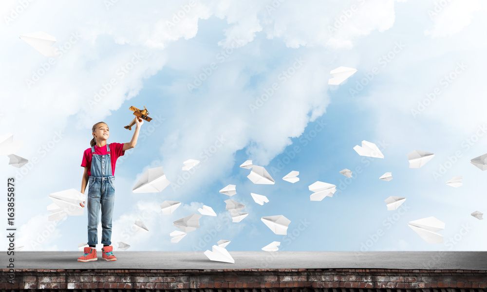 Concept of careless happy childhood with girl dreaming to become pilot Concept of careless happy childhood with girl dreaming to become pilot