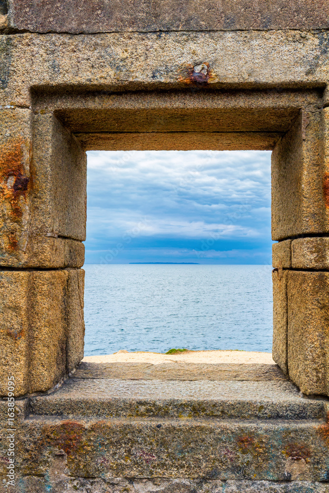 Ocean viewed through window of stone wall