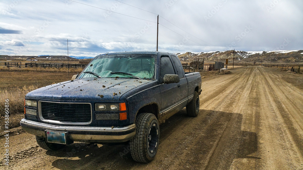 Older Chevy Silverado GMC Sierra Pickup Truck K1500 Off Road in Country side of Wyoming while covered in Mud - obrazy, fototapety, plakaty 