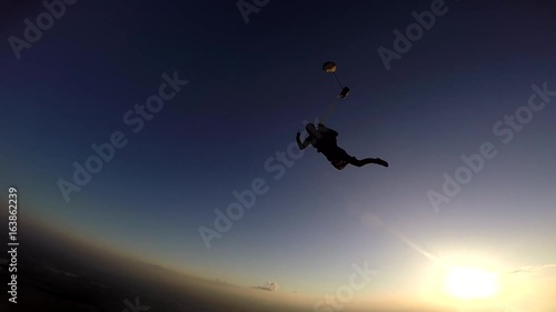 Parachutist opening the parachute at sunset