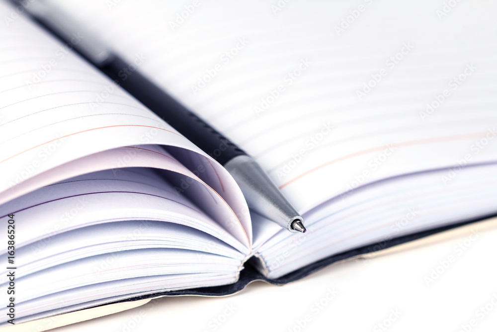 selective focus of ball pen on opened lined diary book selective focus of ball pen on opened lined diary book