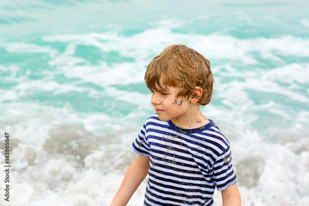 little kid boy running on the beach of ocean little kid boy running on the beach of ocean