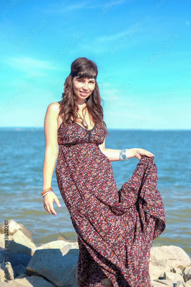 Beautiful young woman standing on the stone on the seashore Beautiful young woman standing on the stone on the seashore