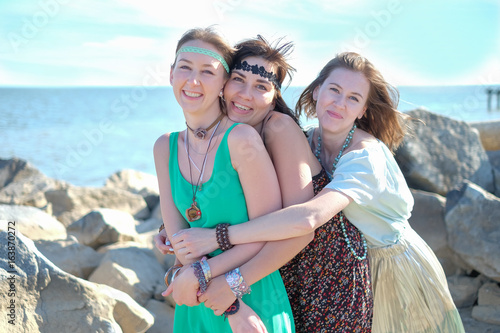 Three happy young hippie girlfriends having fun at the beach