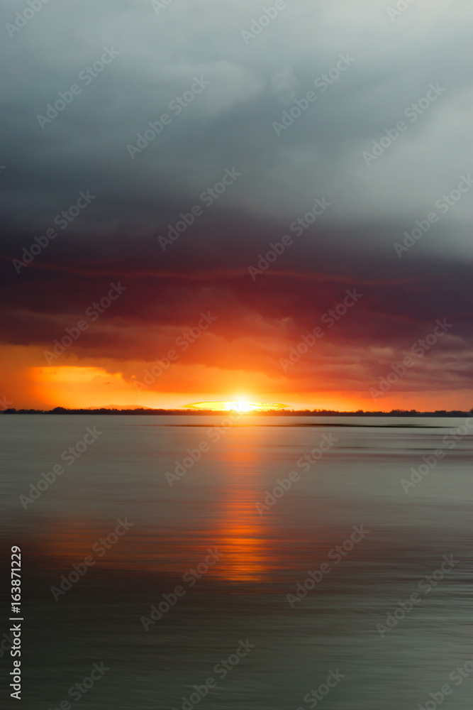 Sunset sky at the lake under rain cloud.