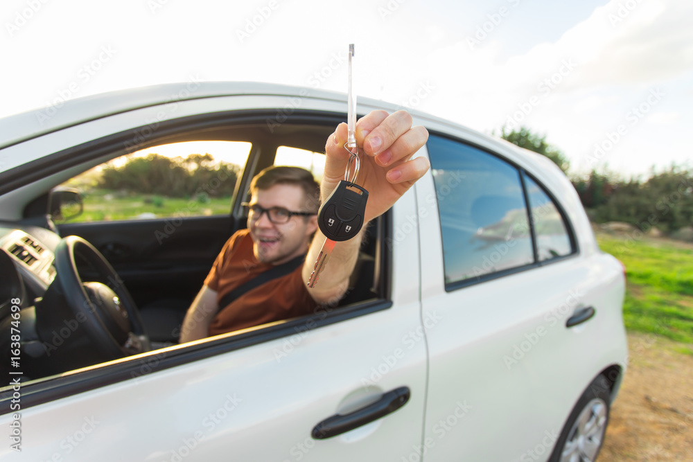 Attractive young happy man showing his new car keys and laughing
