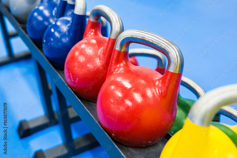 colorful kettlebells in a row in a gym - focus on the front kettlebell