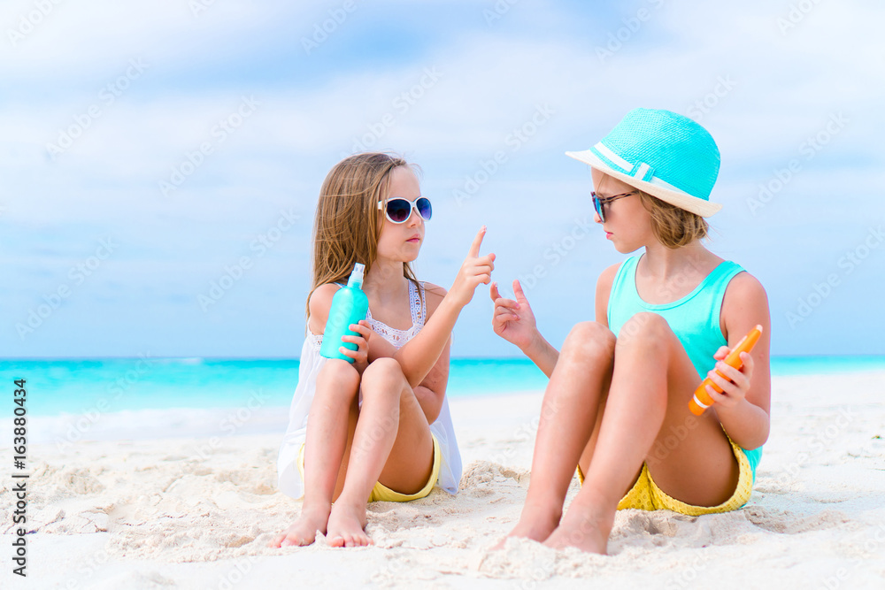 Kids applying sun cream to each other on the beach. The concept of protection from ultraviolet radiation