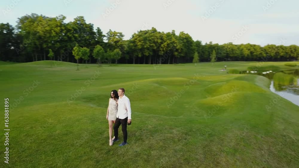 Aerial View Of Young Couple Walking In Summer Park, Circling Drone Shooting Man And Woman Outdoors Aerial View Of Young Couple Walking In Summer Park, Circling Drone Shooting Man And Woman Outdoors