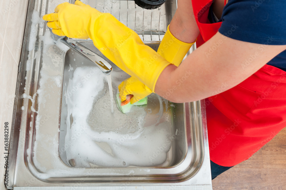 Fototapeta premium Female housekeeper cleaning the kitchen sink