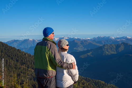 Happy couple of travelers is admiring the dawn in the mountains