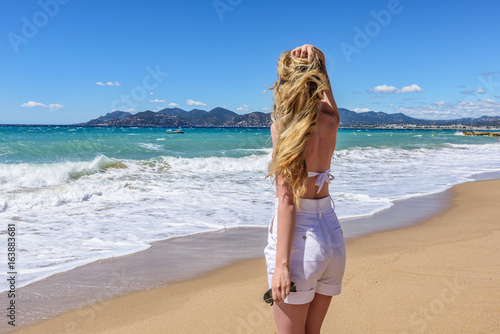 Girl at the beach in Cannes, France. Beautiful Seaside background. Back view