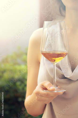 summer pleasure with wine, female hand holding a glass (sunset light vintage effect)