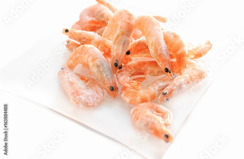 Shrimp are on the small glass dish on a white background.