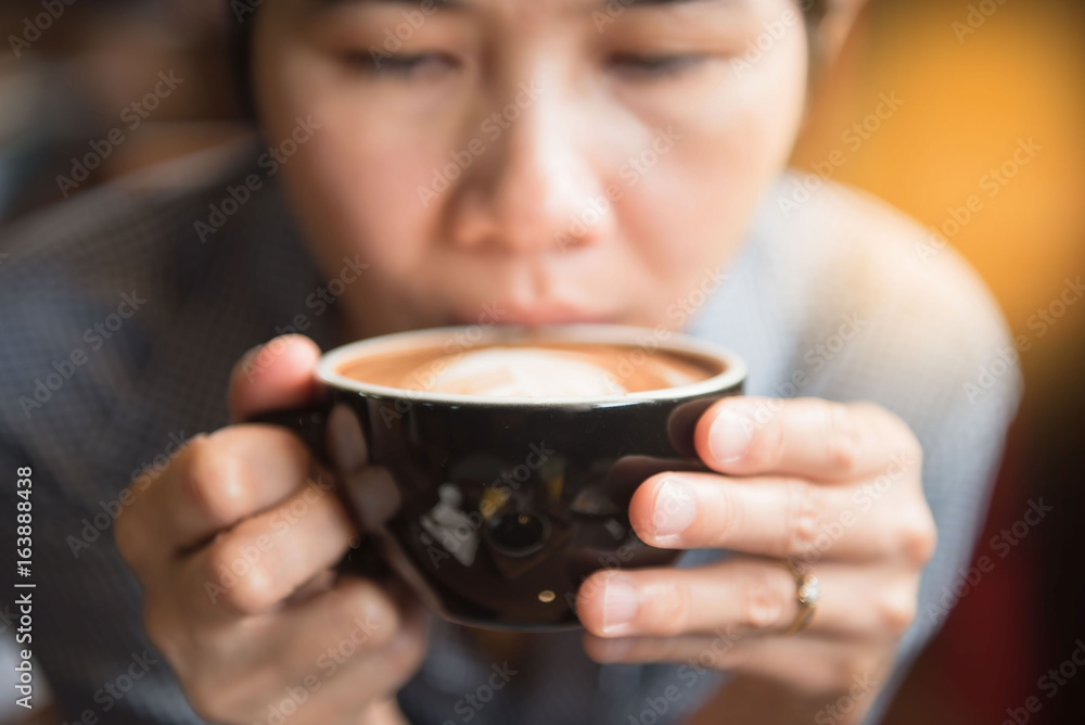 Women holding a hot cup of coffee in hands in coffee shop at morning . Women holding a hot cup of coffee in hands in coffee shop at morning .