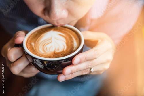 Women holding a hot cup of coffee in hands in coffee shop at morning .