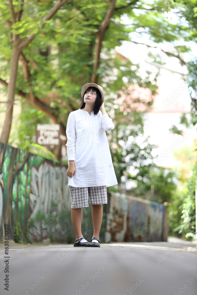 Asian young woman thinking and looking portrait with green tree background Asian young woman thinking and looking portrait with green tree background