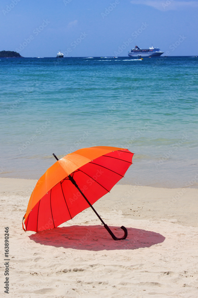 orange umbrella  at the beach with a turquoise sea