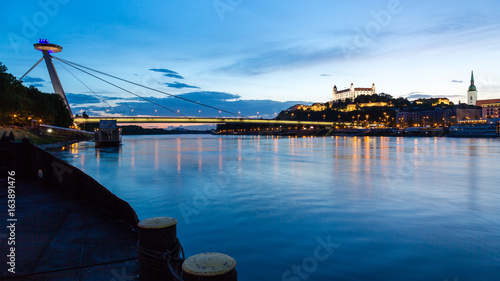 Bratislava, New Bridge, Castle, Cathedral during dusk from a boat on river Danube, wide 16:9