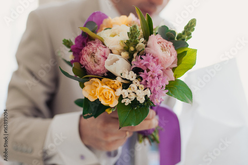 Wedding groom with bride's bouquet of flowers outside