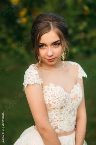 Young girl in wedding dress in park posing for photographer. portrait